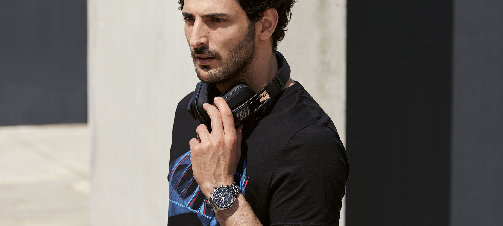 Man in outfit van BMW M Collection, met Bluetooth-hoofdtelefoon, horloge en T-shirt. Man in outfit van BMW M Collection, met Bluetooth-hoofdtelefoon, horloge en T-shirt.